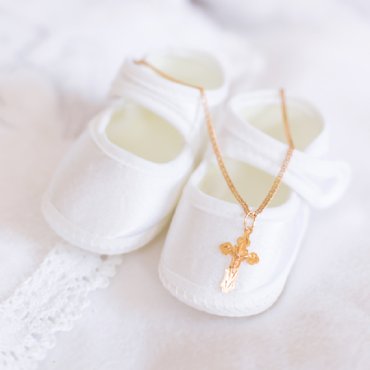 White baby shoes with a cross necklace
